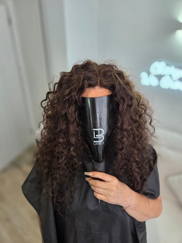 Client with full curly hair after a hair system fitting, face not shown